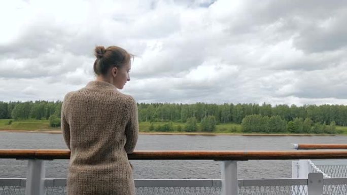 年轻女子站在游轮甲板上，看着河流和风景