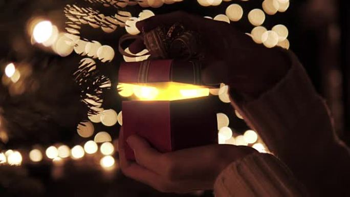 女人用金色魔灯打开红色圣诞礼盒
