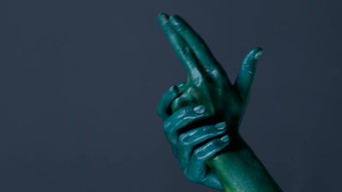时装模特的双手涂成绿色，用手势和射击显示枪支。时尚视频。