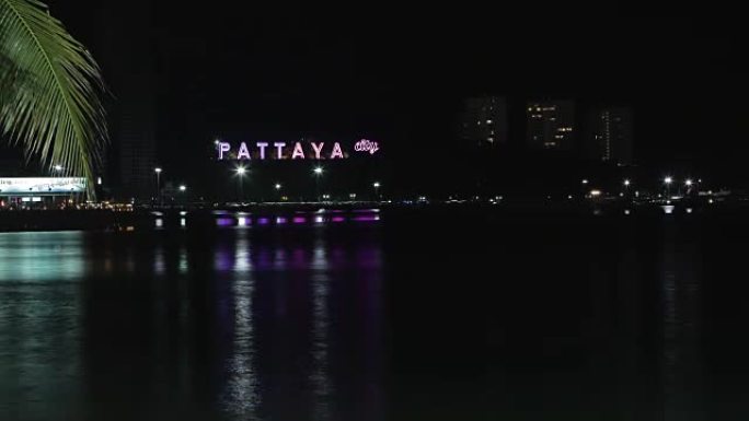 夜晚岩石上刻有芭堤雅铭文的海边景色。视频。夜晚芭堤雅湾海景。泰国春武里府芭提雅市鸟瞰图夜景