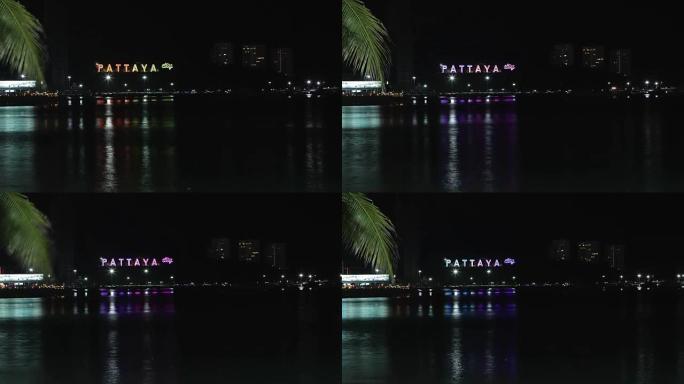 夜晚岩石上刻有芭堤雅铭文的海边景色。视频。夜晚芭堤雅湾海景。泰国春武里府芭提雅市鸟瞰图夜景