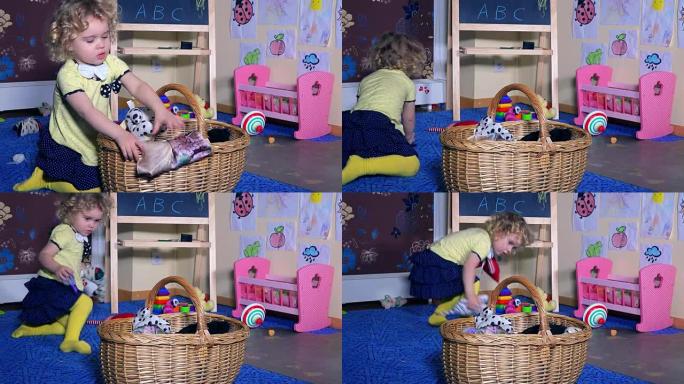 蹒跚学步的女孩把玩具放在柳条篮上。家里凌乱的房间