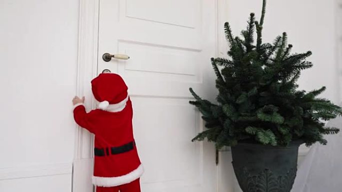 穿着圣诞老人西装的小孩试图打开门回家