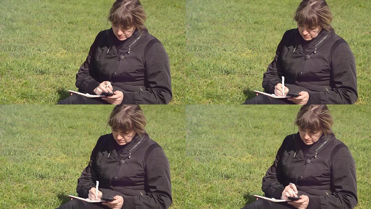 一个女人在看电话，在笔记本上写字