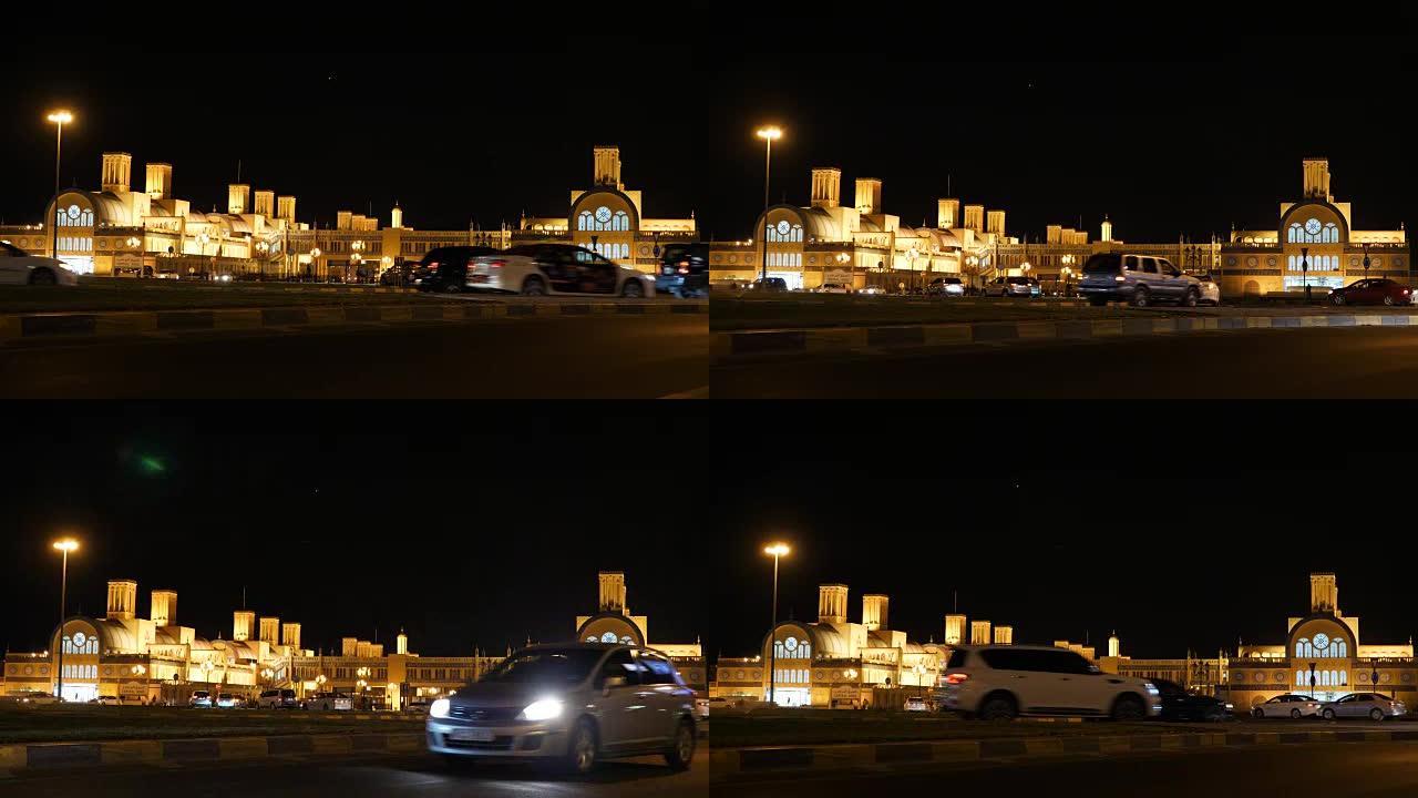 阿拉伯联合酋长国沙迦中央露天市场的夜景。汽车开着灯经过。照明建筑。建筑艺术作品。市场建设。