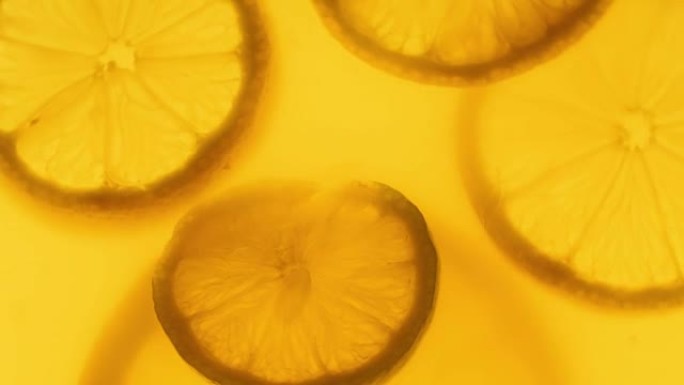 全高清特写视频背光柠檬片漂浮在罐子里的橙汁中