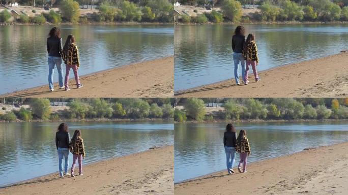一个女人和一个女孩在河边散步。母女俩沿着河岸散步