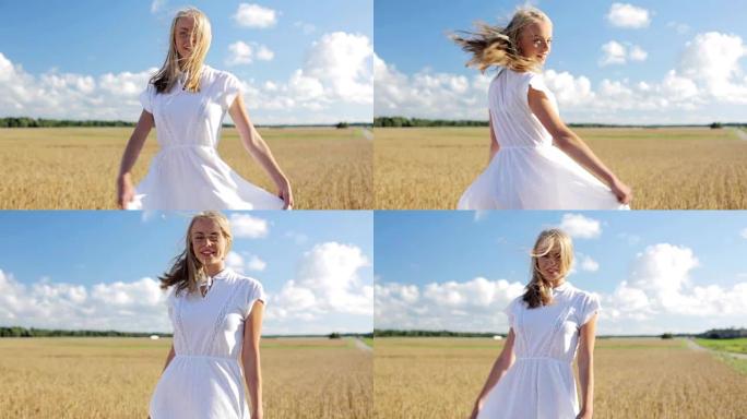 微笑的年轻女子在谷物田里穿着白色连衣裙