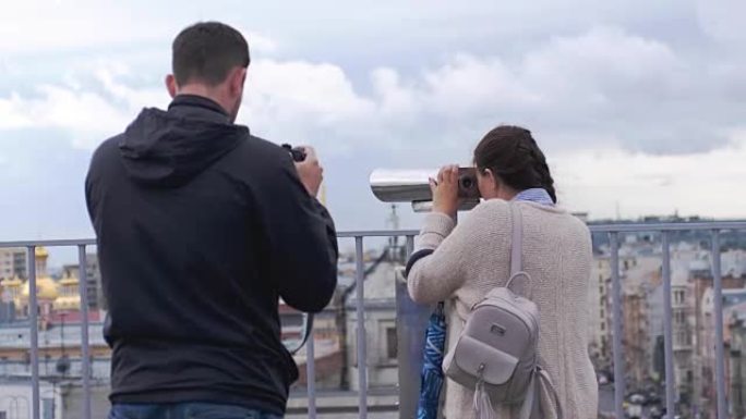 女人在圣彼得堡与游客双筒望远镜一起旅行和观赏，她的朋友为她拍照。3840x2160