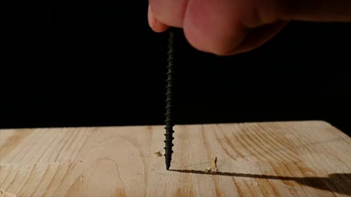 这个人用螺丝刀将螺丝拧入木板