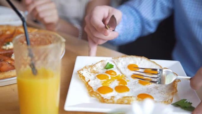 男性的手在餐厅用刀叉切一个美味又有用的煎蛋
