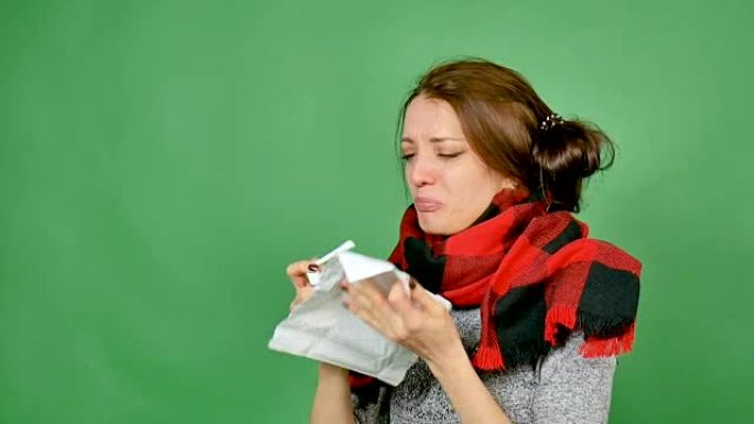 一个患有流感的迷人黑发女人的肖像。这个女孩感冒了，发热了，脖子上裹着围巾。她用喷雾剂喷喉咙。心绞痛，