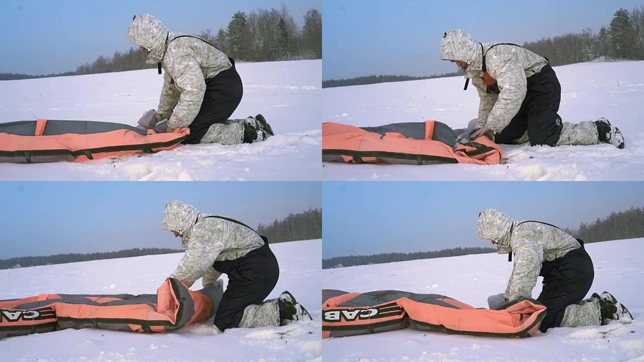 运动员坐在白雪皑皑的地面上，包裹着降落伞。运动器材中的跳伞运动员正在弄皱降落伞