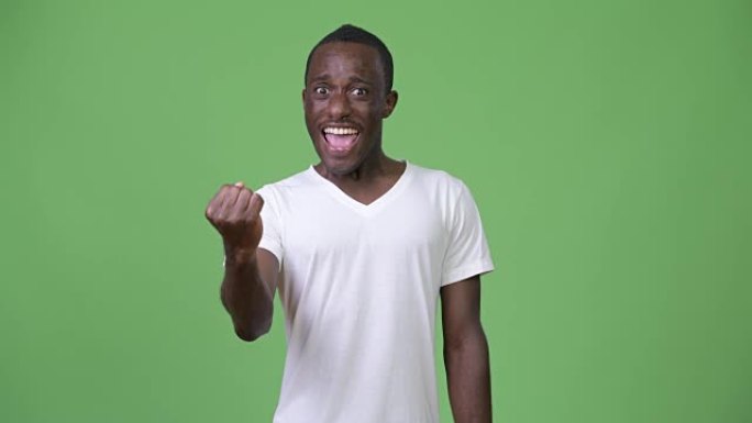年轻快乐的非洲男子在绿色背景下举起拳头