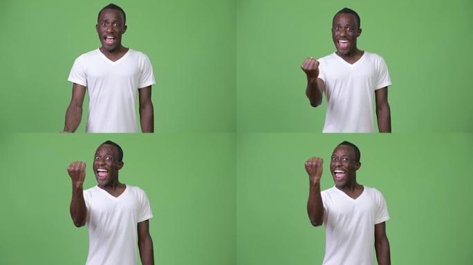 年轻快乐的非洲男子在绿色背景下举起拳头