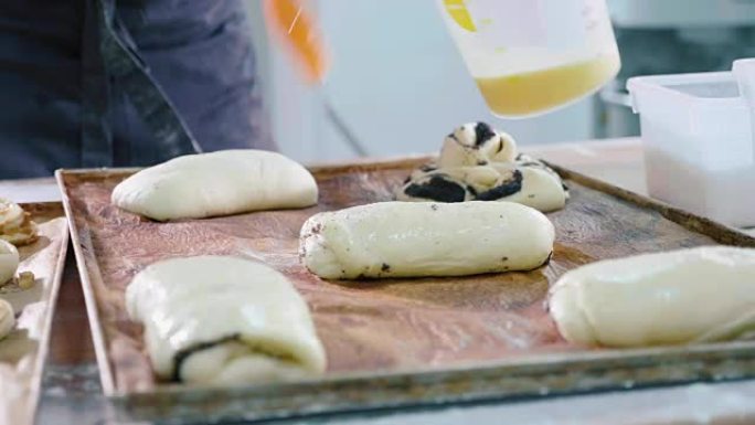 面包师在输入烤箱之前先润滑甜味烘烤的顶面
