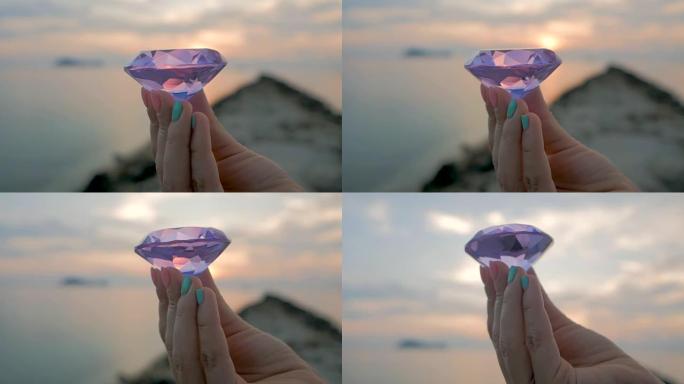 女性手中的紫色钻石水晶，特写，日落背景
