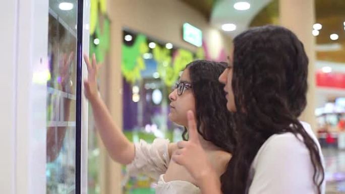 两个漂亮的女孩使用互动面板在商场购物