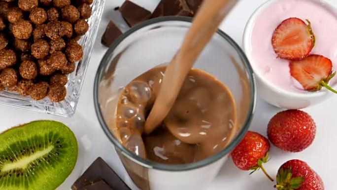 巧克力和牛奶一起在玻璃杯中流动作为早餐