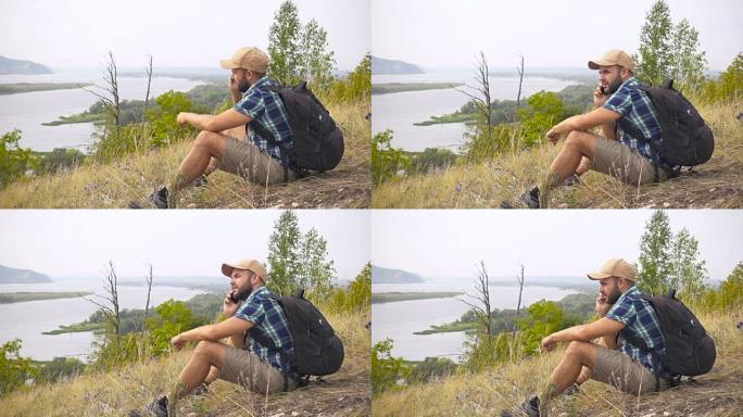 旅游男子他坐在山里，在电话里聊天。树林里背着背包的男人。徒步旅行。森林之旅。露营。休闲。生态旅游。狂