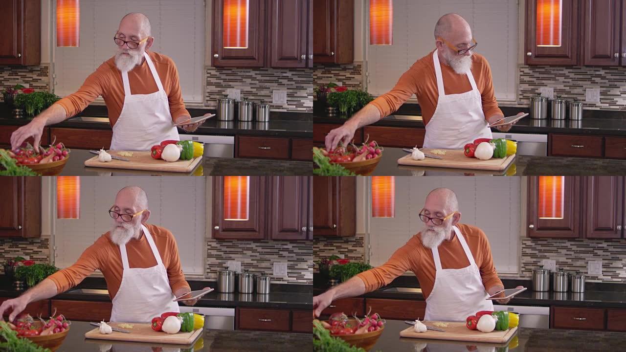 老厨师在使用平板电脑时伸手去拿些蔬菜