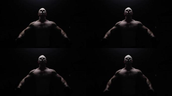 Shirtless bodybuilder posing in dark