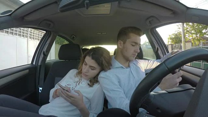 恋人背靠背坐在车里，在社交媒体上玩手机