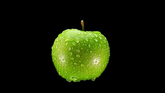 美丽的绿色苹果与水滴在黑色背景上旋转，特写