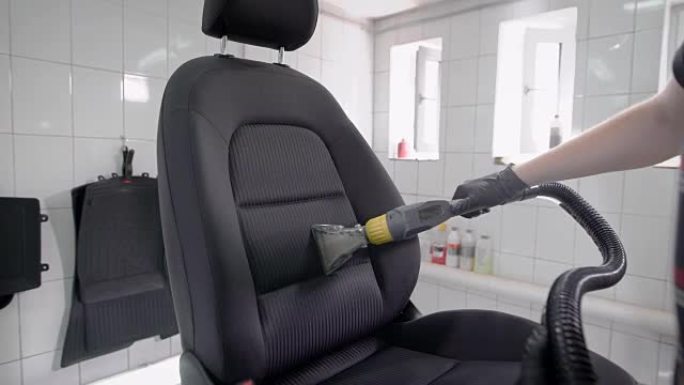 一名男子用吸尘器吸走洗车中的汽车座椅的特写镜头