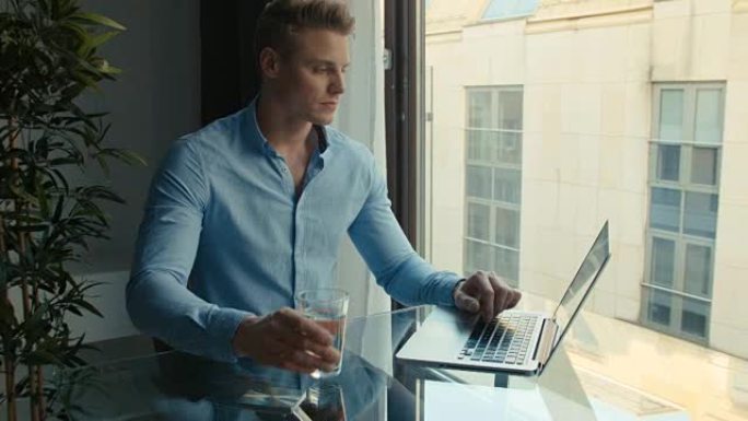 在室内用笔记本电脑工作的英俊年轻人。