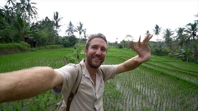 在亚洲旅行的年轻人在印度尼西亚巴厘岛的稻田露台附近用相机自拍。