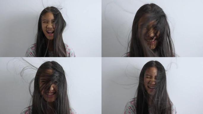 快乐亚洲女孩在白色背景上玩头发吹的慢动作镜头