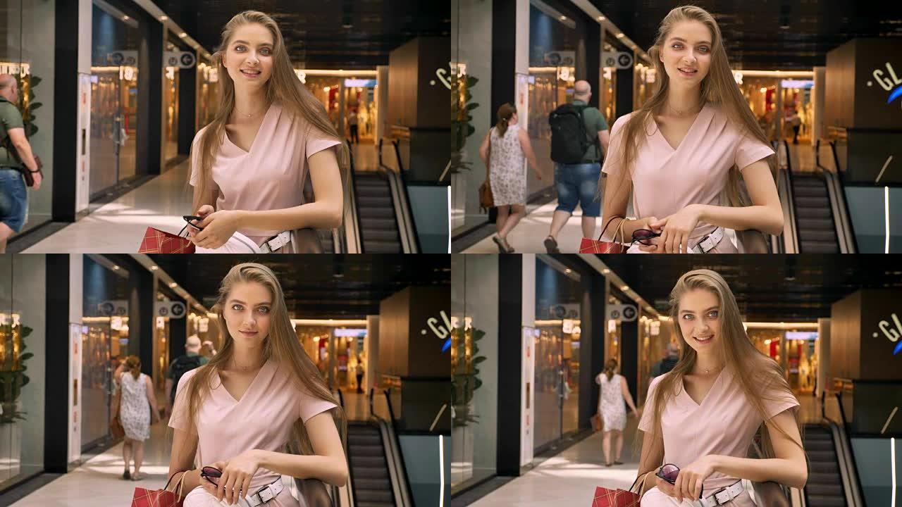 年轻迷人的女孩站在商场，提包，看相机，购物概念，时尚概念