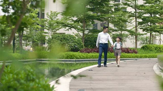 亚洲父亲护送儿子在花园慢动作中上学