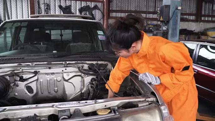 dolly从正面拍摄: 亚洲年轻的女汽车修理工在汽车发动机上工作