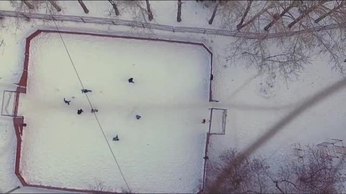 在雪地里踢足球的鸟瞰图。股票。冬天下雪的足球场鸟瞰图。一个小镇，树木，冬天和雪中的运动场。雪地下的冬
