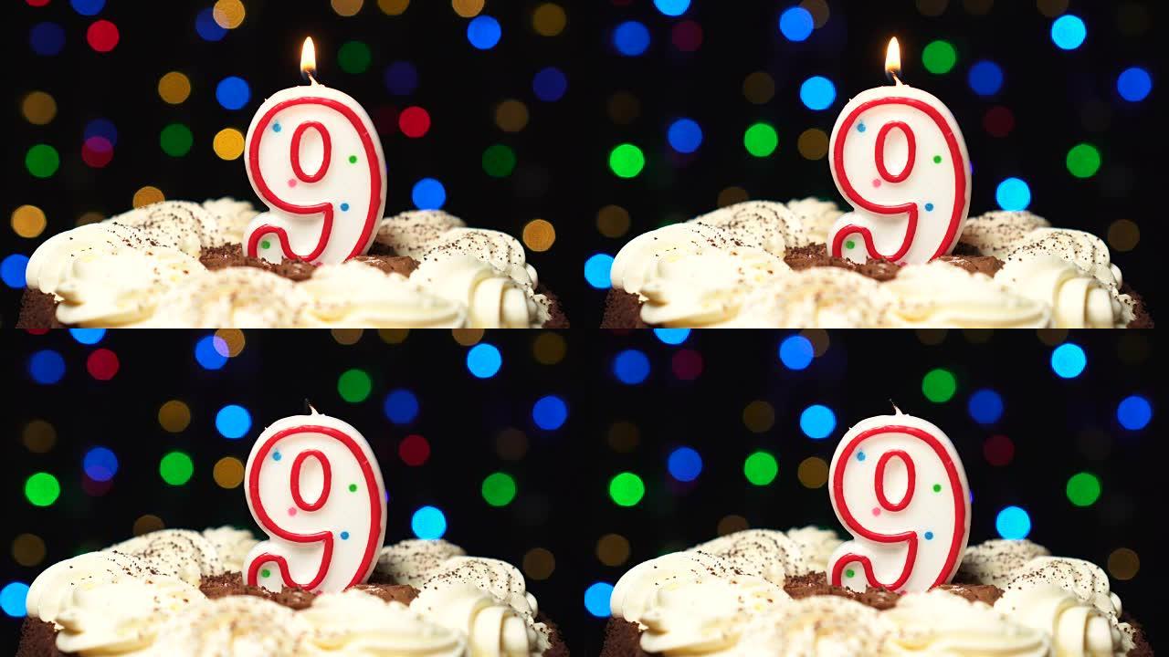 蛋糕上的9号-九岁生日蜡烛燃烧-最后吹灭。彩色模糊背景