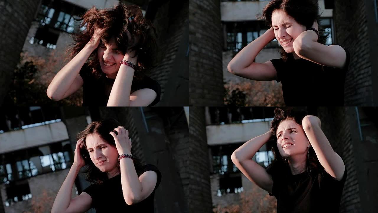 一名年轻女子站在废弃的工厂前，情绪激动地将头发脱去