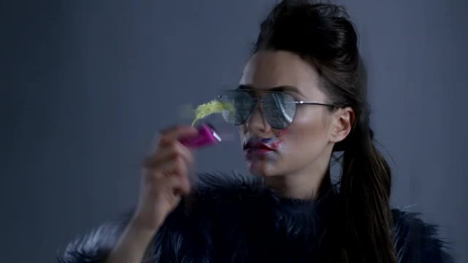 皮草和太阳镜的高级时装模特拿着粉色指甲油瓶。时尚视频。