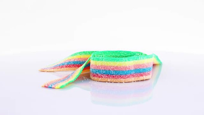 彩色彩虹酸带糖糖果在转盘上旋转。孤立在白色上。特写宏。可循环。