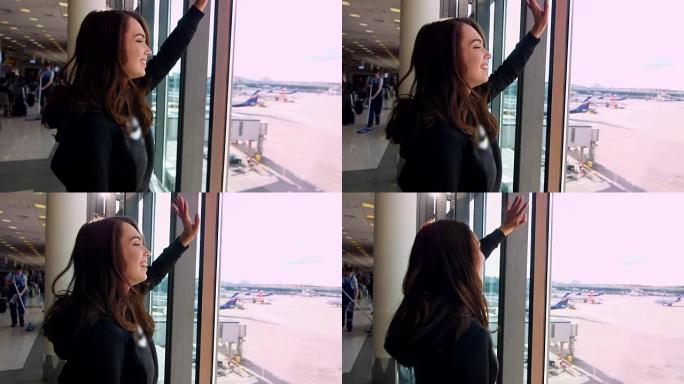 年轻女孩在机场向窗户挥手告别