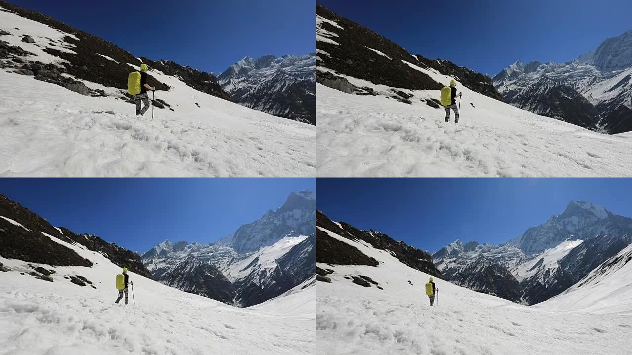 一个背着背包的女孩在雪地里爬到山上。尼泊尔喜马拉雅山