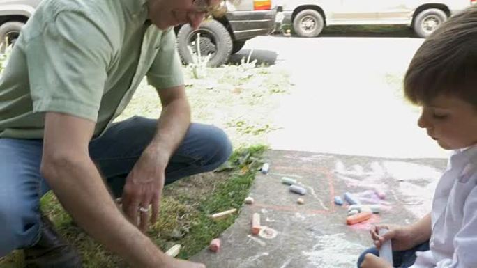 父子俩一起在人行道上用粉笔画画