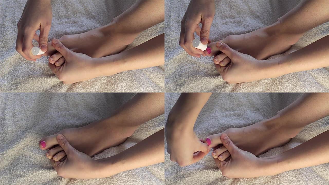 女人的手画脚趾甲。女孩在脚上画指甲粉红漆