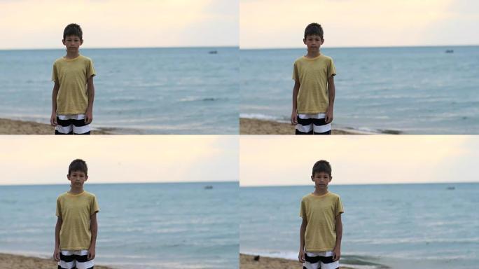 男孩站在海边的海滩上，看着相机