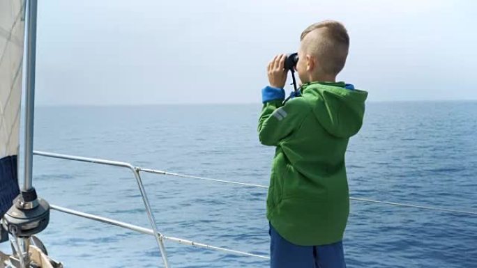 小男孩站在游艇上，看着双眼