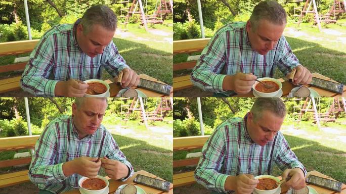 男子在户外夏季咖啡馆吃汤