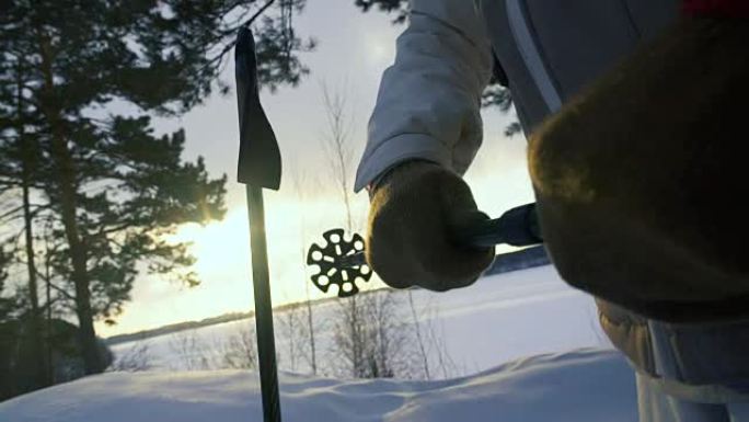 徒步旅行者在雪山中使用手杖，日落时分