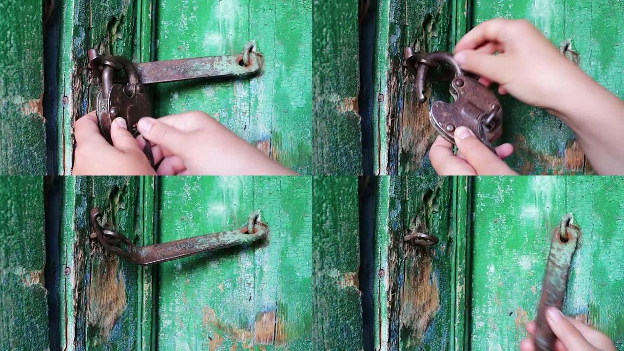 门上的老式铁锁已被绿色油漆剥落。母手开启和关闭锁