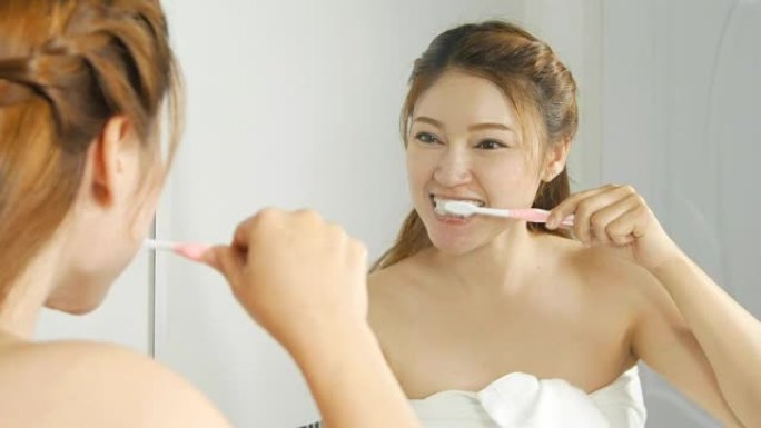 浴巾女人在浴室用镜子刷牙